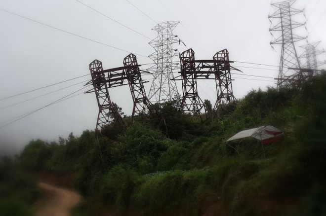 At a hilltop near Kathmandu city. The old ghiring cables, now defunct, go underneath the bijuli transmission lines. These towers separate Kathmandu from Makwanpur district.